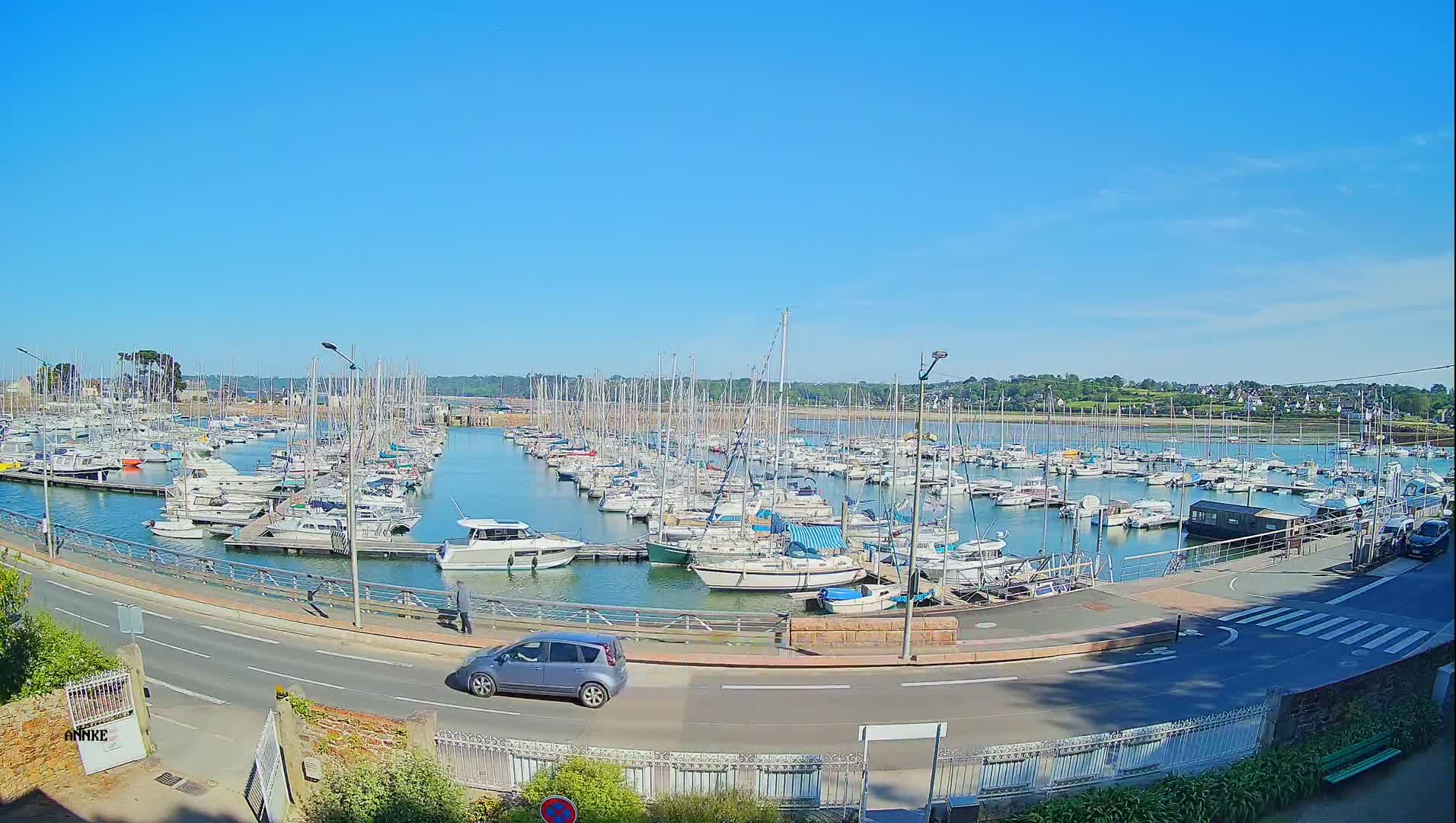 A marina filled with numerous sailboats and motorboats on a sunny day.