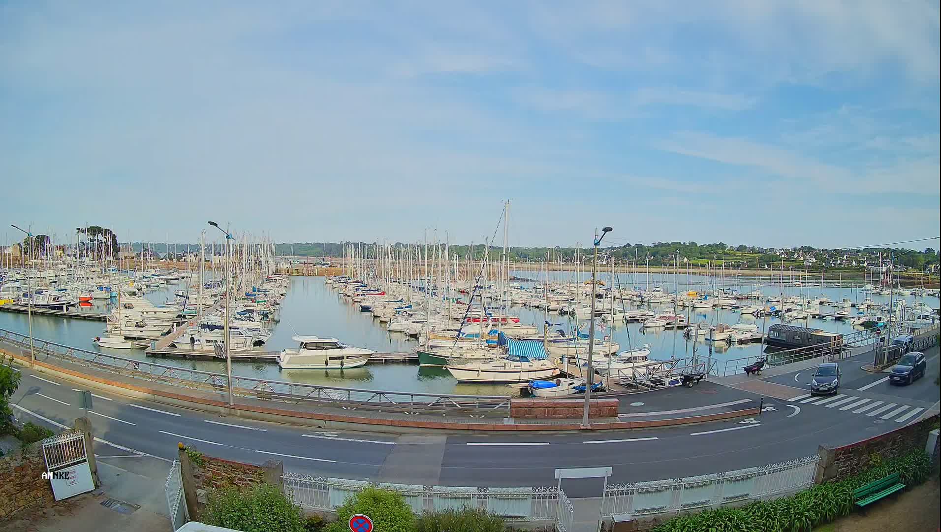 A marina filled with numerous sailboats and motorboats is seen on a partly sunny day.