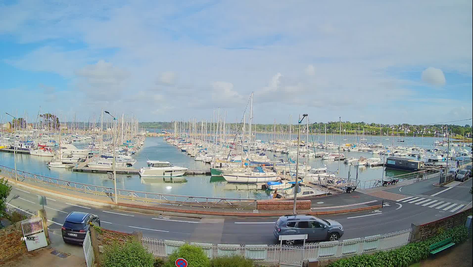 A marina filled with numerous sailboats and motorboats under a partly cloudy sky.