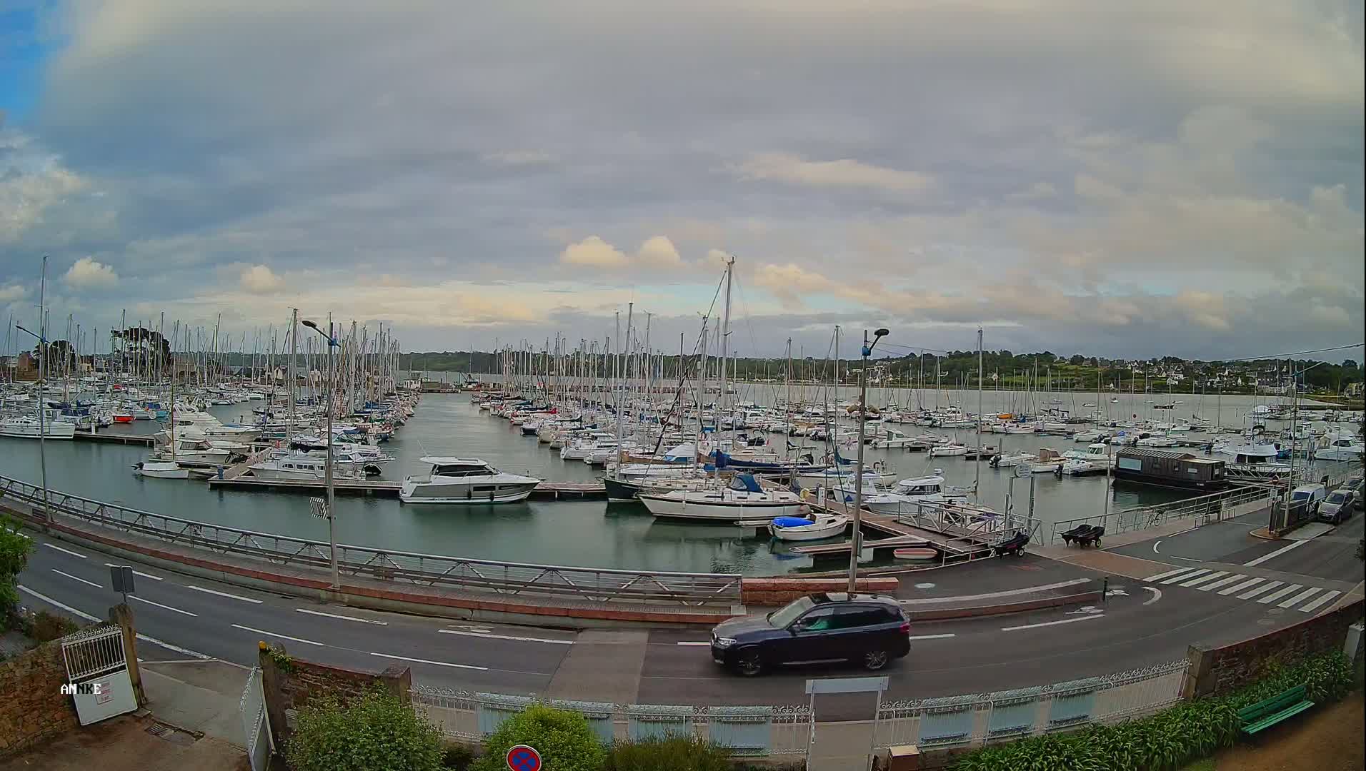 A marina filled with numerous sailboats and motorboats under a partly cloudy sky.