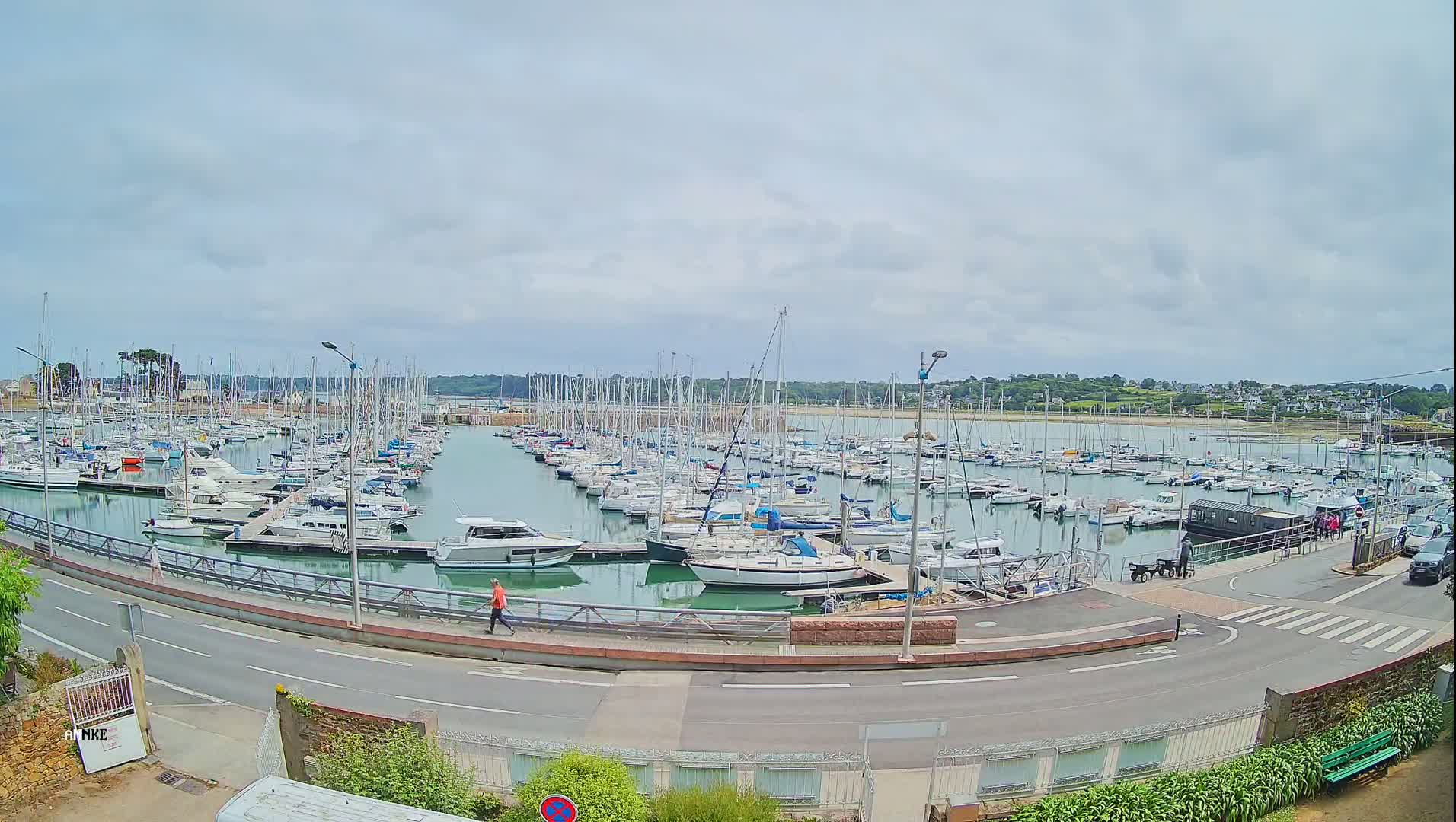 A marina filled with numerous sailboats and motorboats under a cloudy sky.