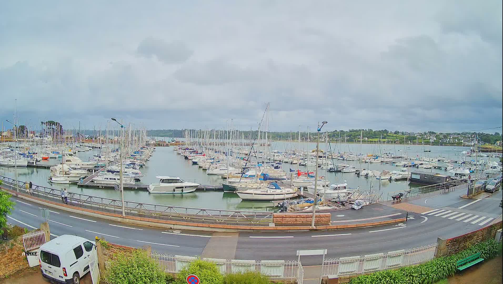 A harbor filled with numerous sailboats and motorboats under a cloudy sky.