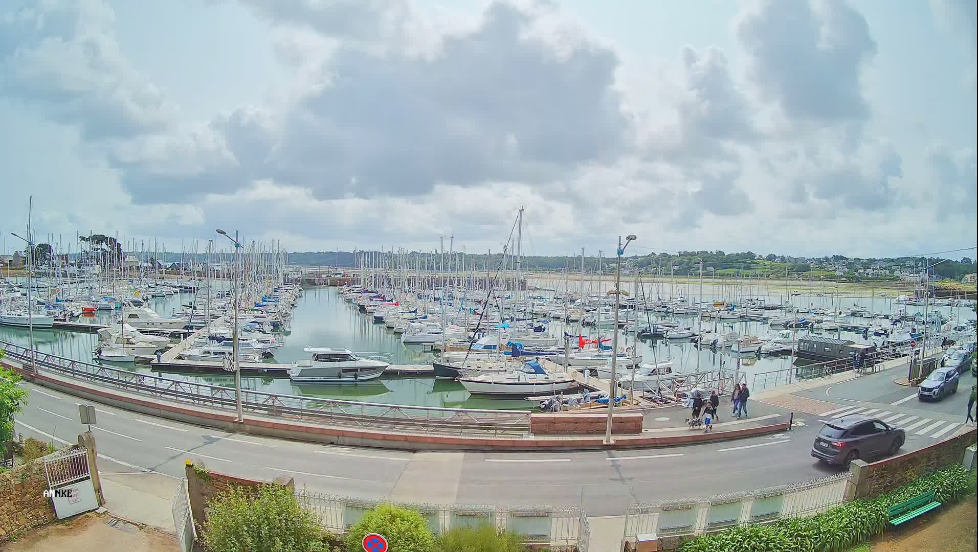 A harbor filled with numerous sailboats and motorboats under a partly cloudy sky.