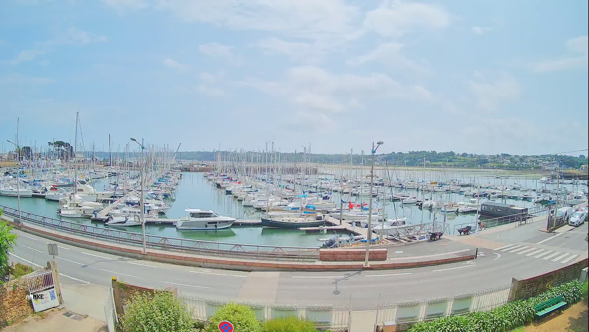 A marina filled with numerous sailboats and motorboats under a partly cloudy sky.