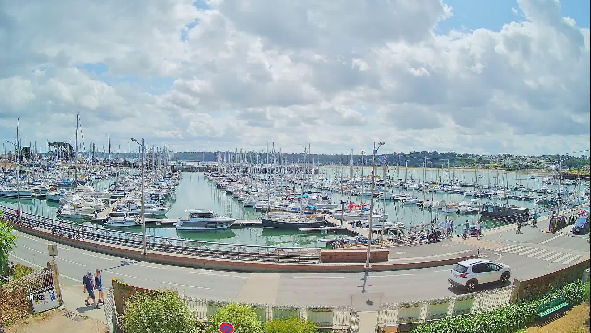 A large marina filled with sailboats and motorboats under a partly cloudy sky.