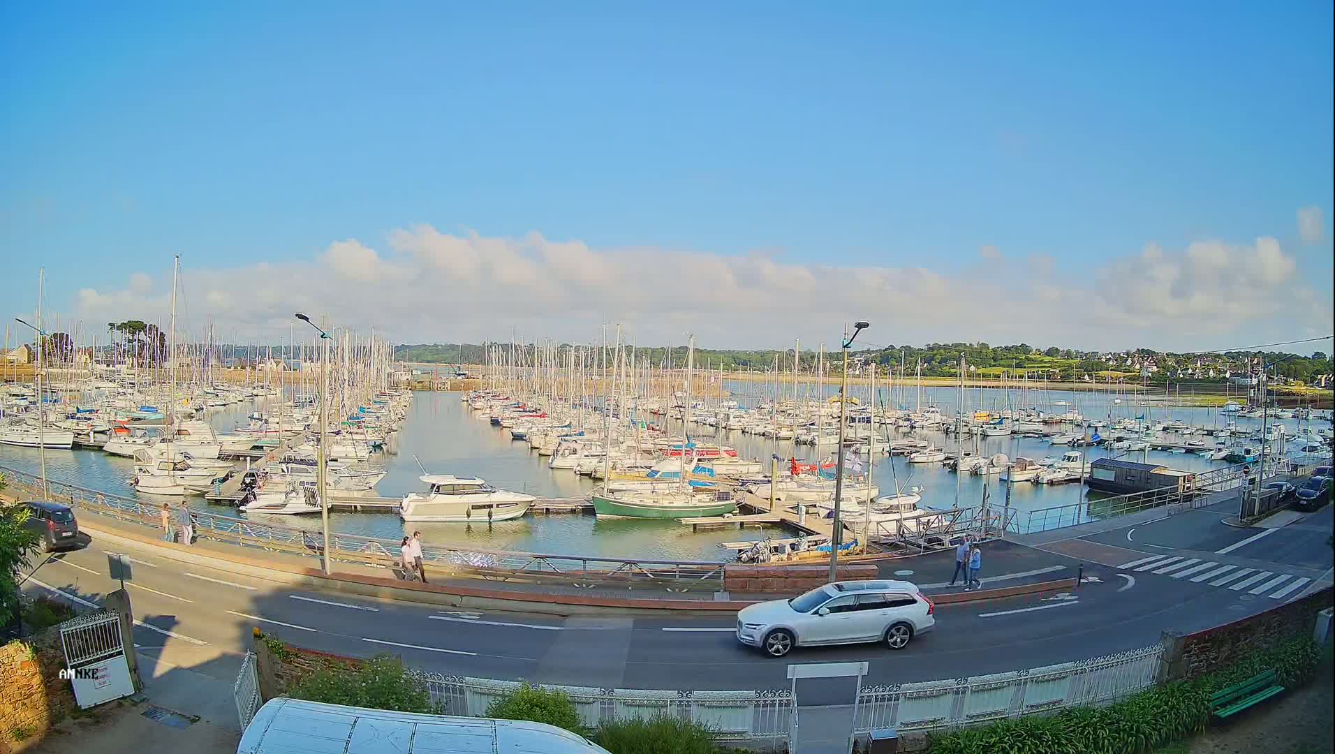 A marina filled with numerous sailboats and motorboats under a mostly sunny sky with a few scattered clouds.