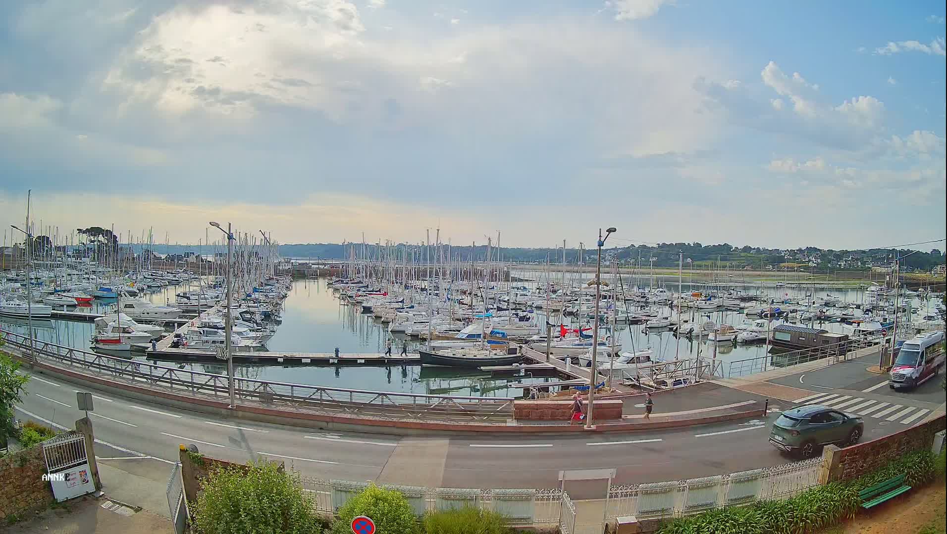 A marina filled with numerous sailboats and motorboats under a partly cloudy sky.