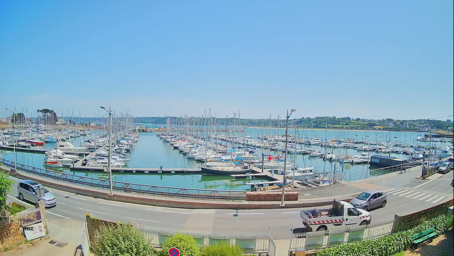 A harbor filled with numerous sailboats and motorboats under a clear, sunny sky.