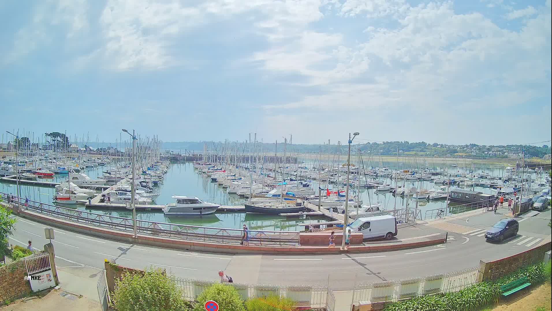 A large marina filled with numerous sailboats and motorboats is seen on a partly cloudy day.