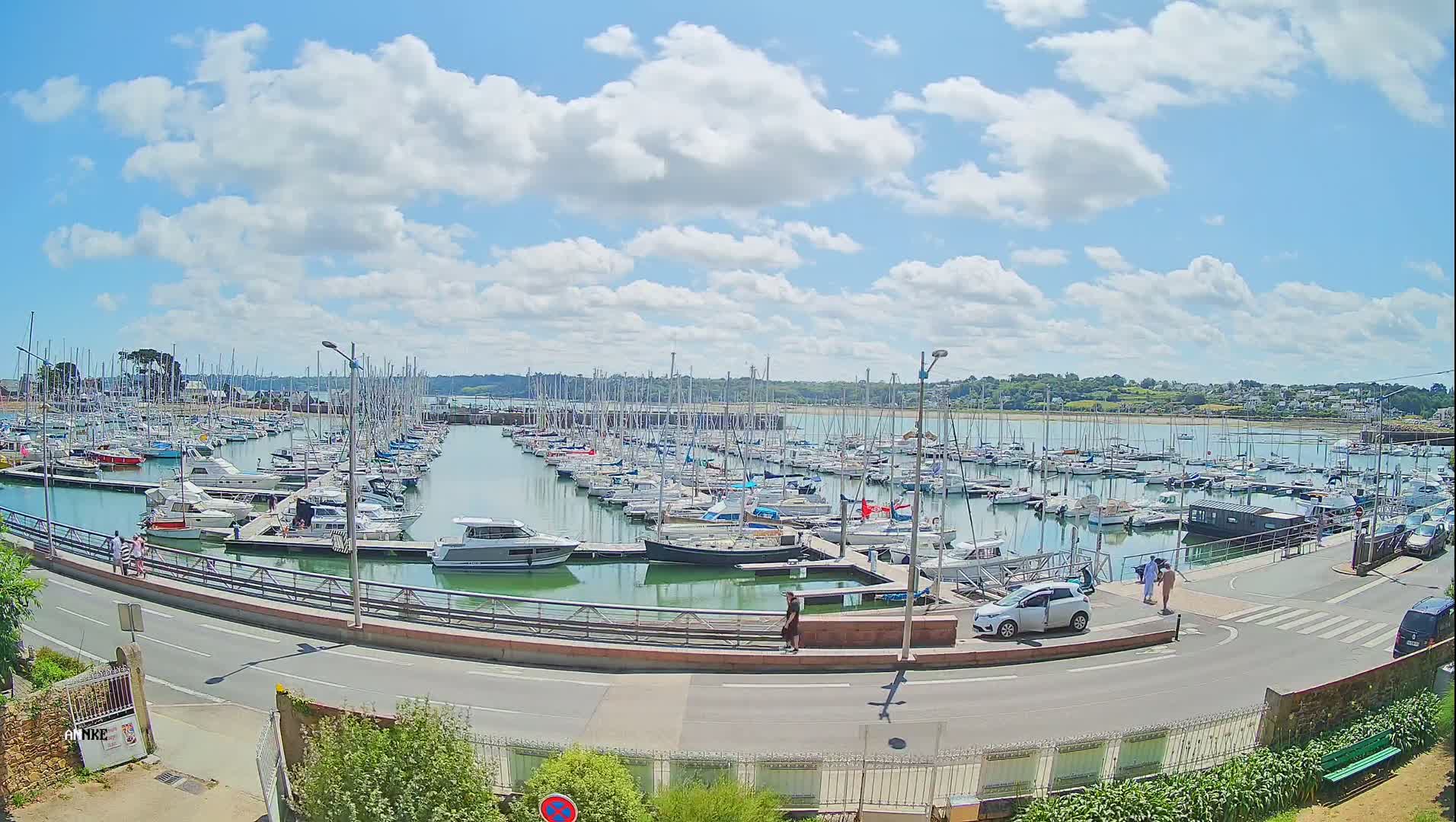 A marina filled with numerous sailboats and motorboats under a partly cloudy sunny sky.