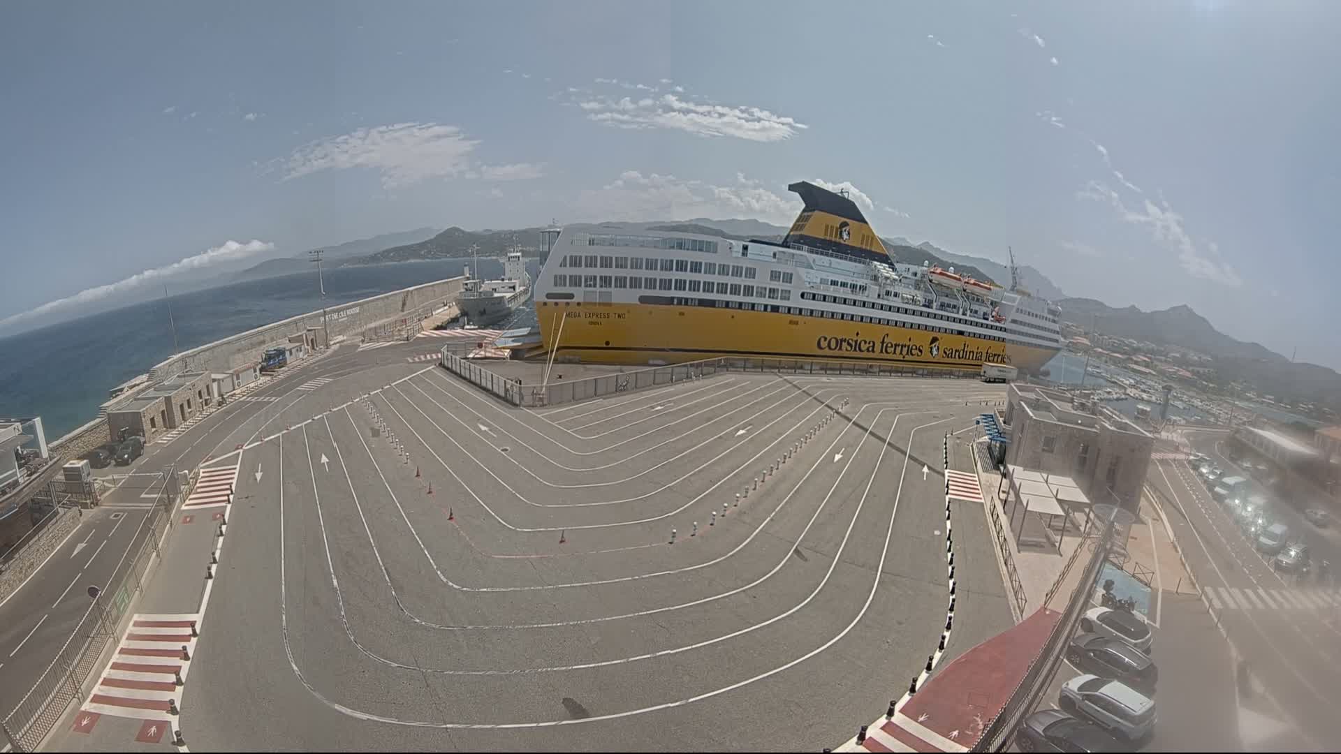 A large yellow and white ferry is docked at a port on a sunny day with clear skies and calm waters.