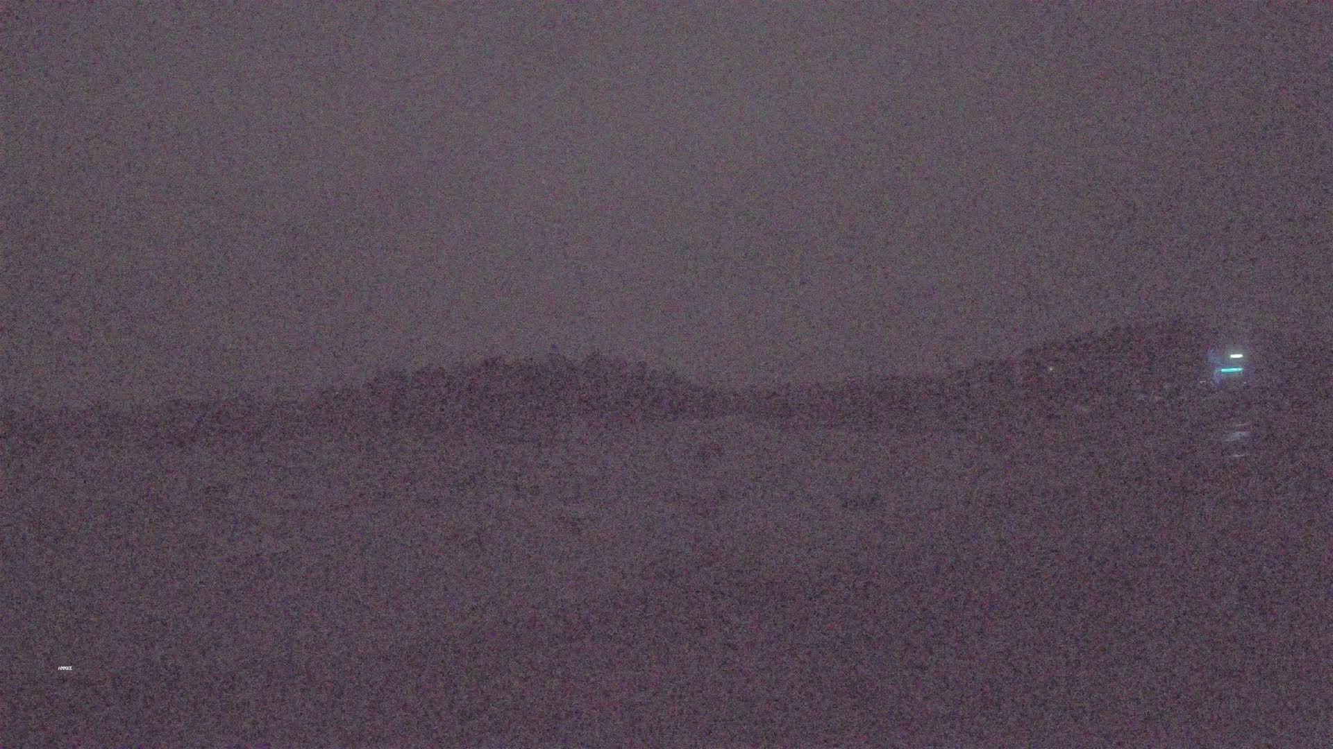 A hazy, dark landscape shows a distant hill under a dusky sky.