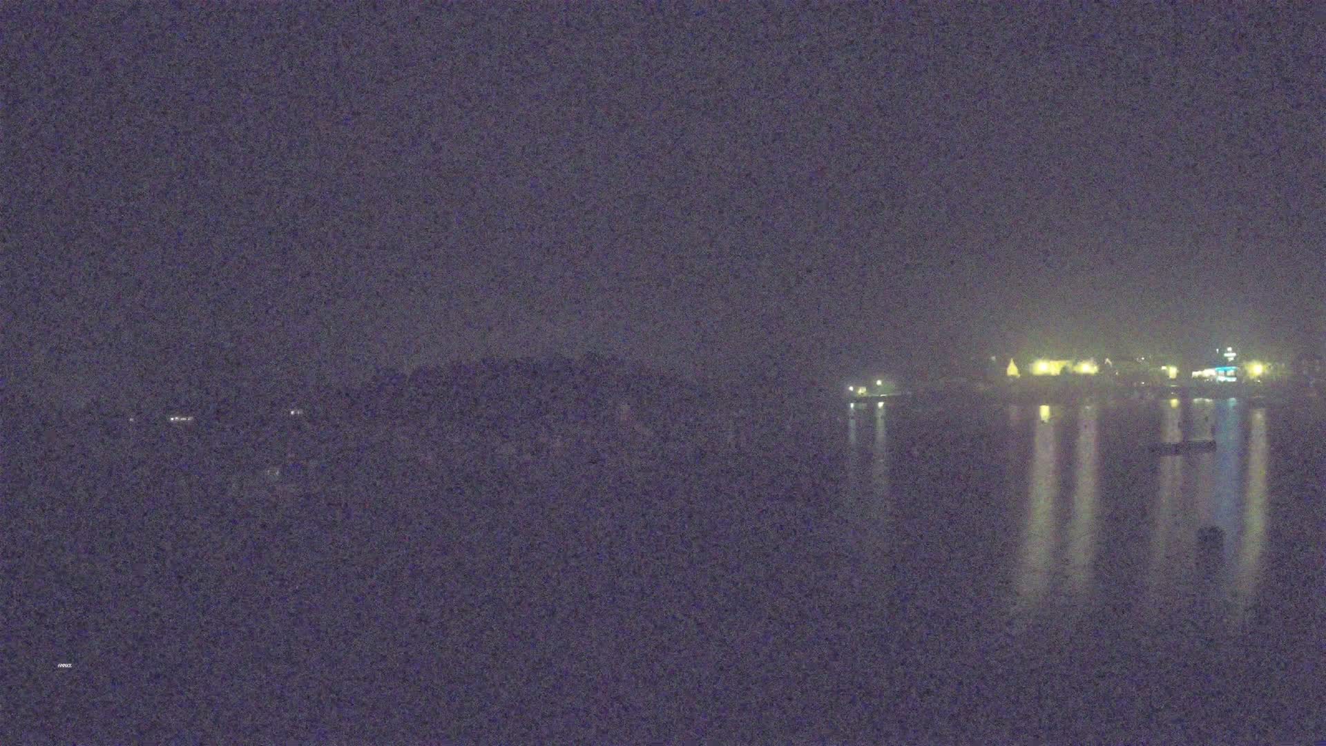 A nighttime view of dimly lit buildings across a calm body of water.