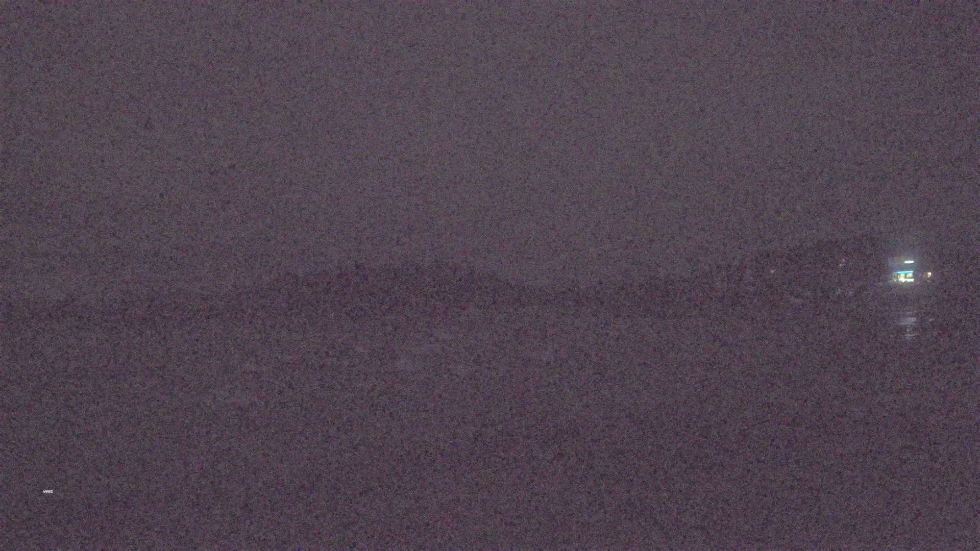 A dark, blurry image shows a body of water under a dark, overcast sky at night.