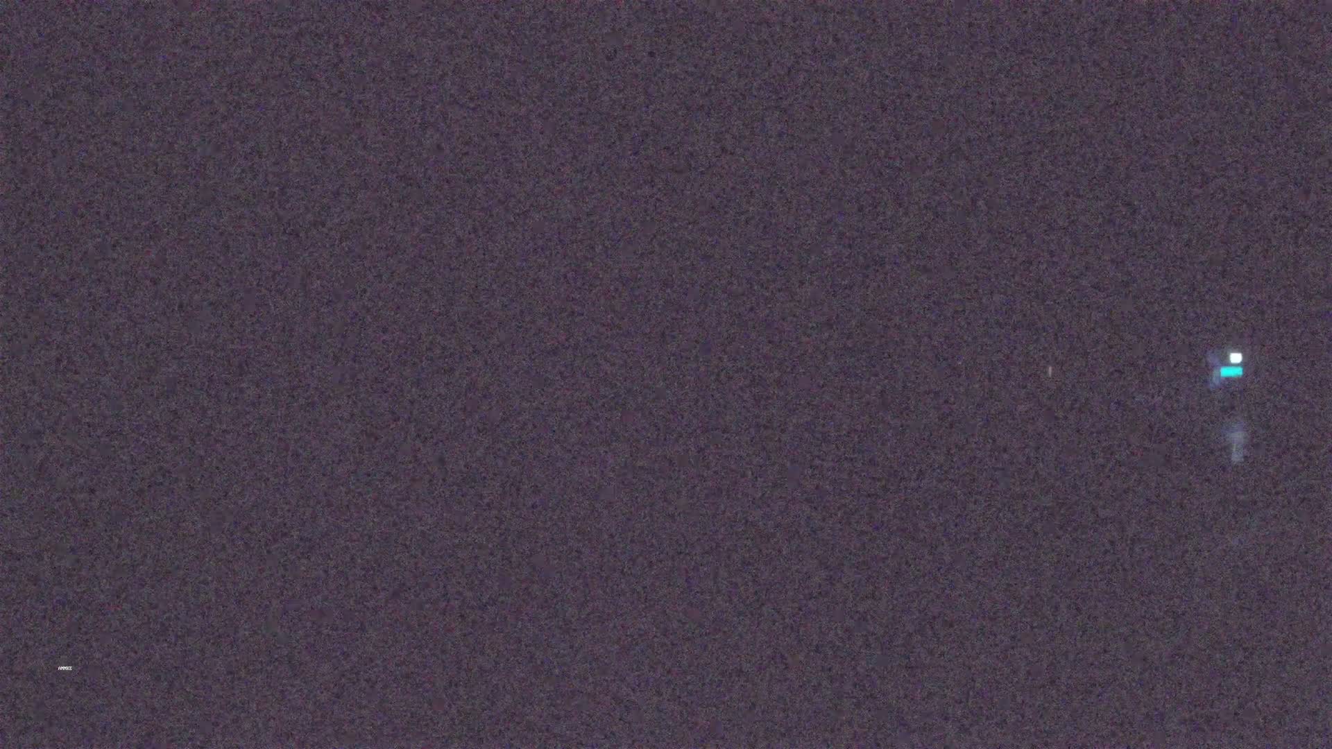 A dark gray textured background with a few small, bright pixels.