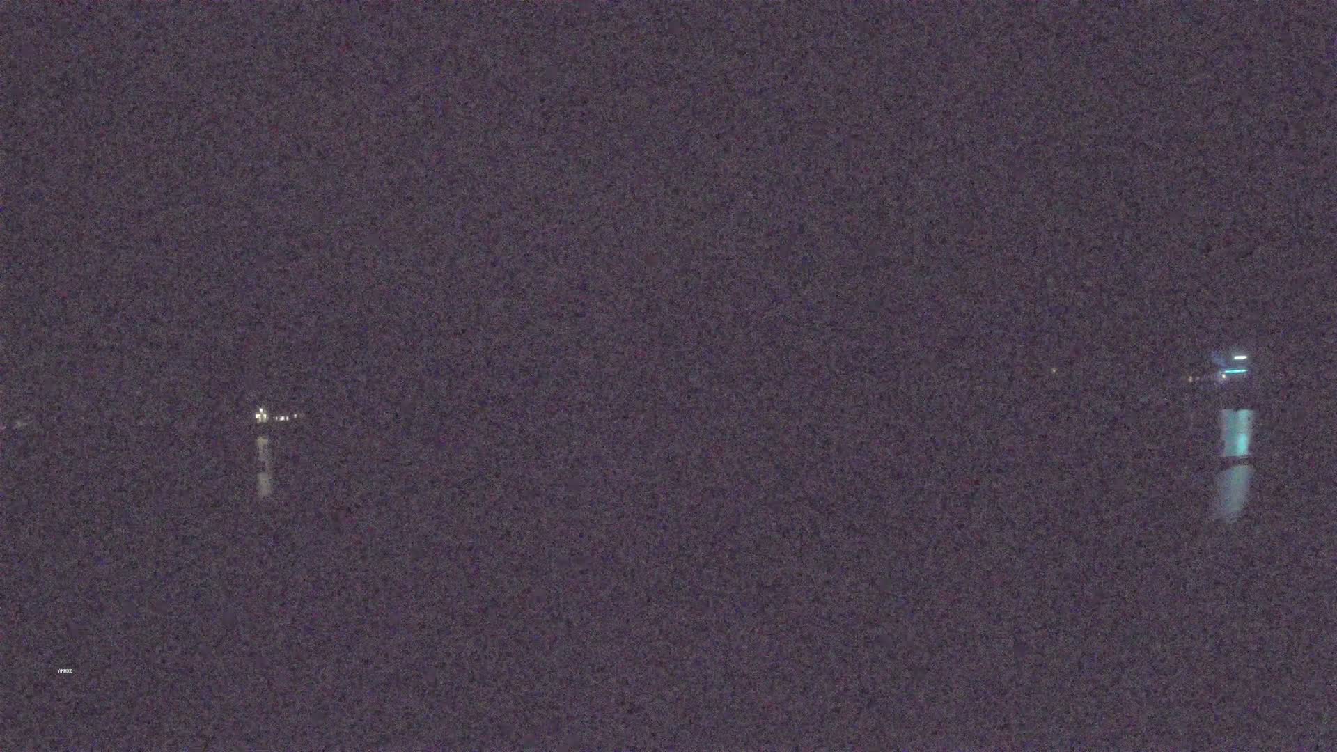 A nighttime, blurry image shows faint lights across a dark body of water.
