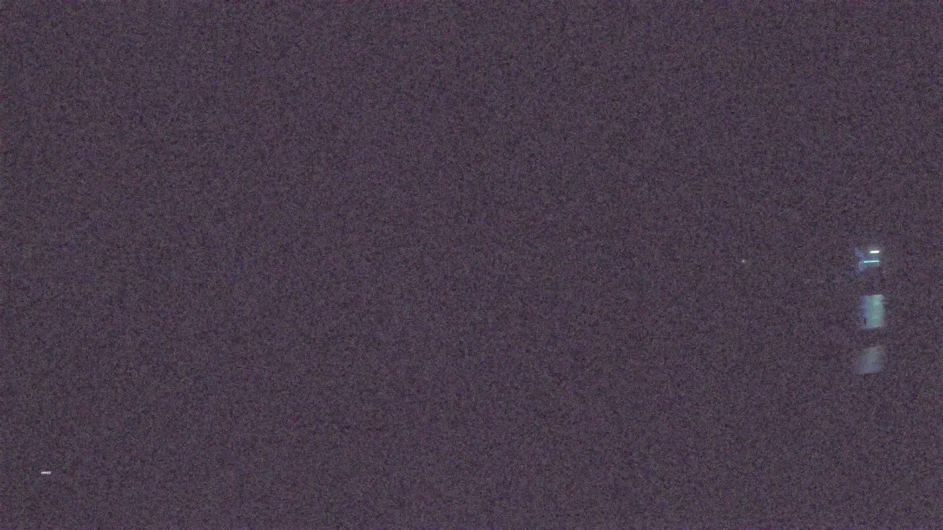 A blurry, dark image shows a faint, vertical light source at night.