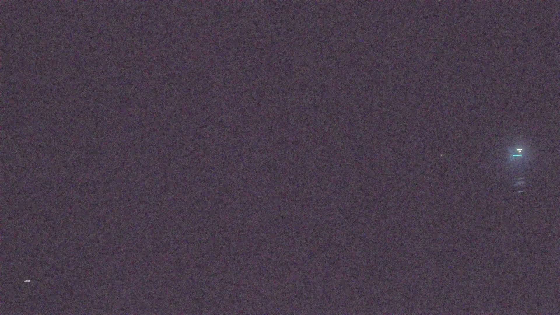 A grainy, dark image shows a single, distant light source at night.