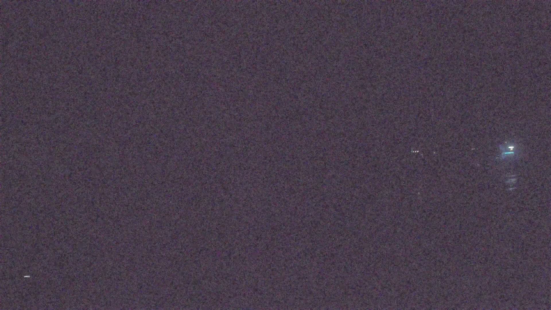 A nighttime, blurry image shows faint lights in the distance.