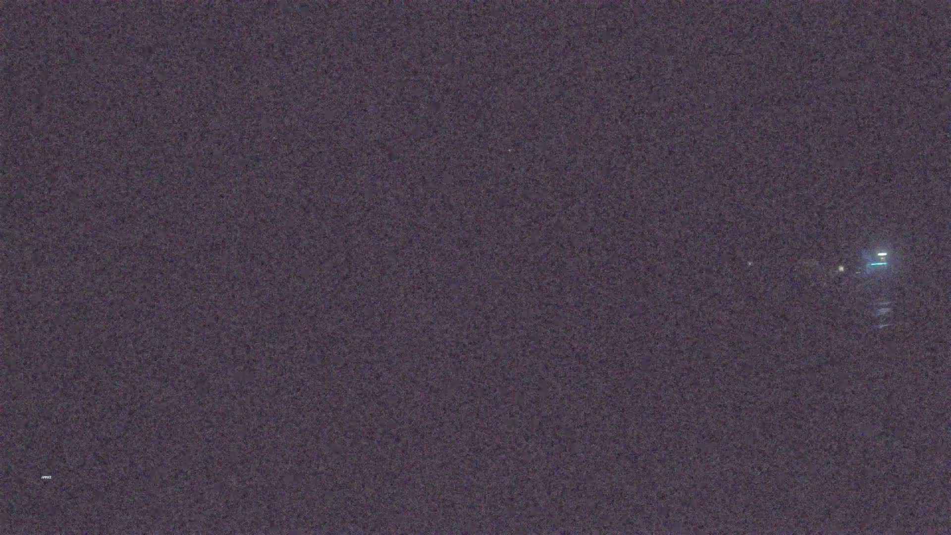 A nighttime, blurry image shows a few distant lights in the dark.