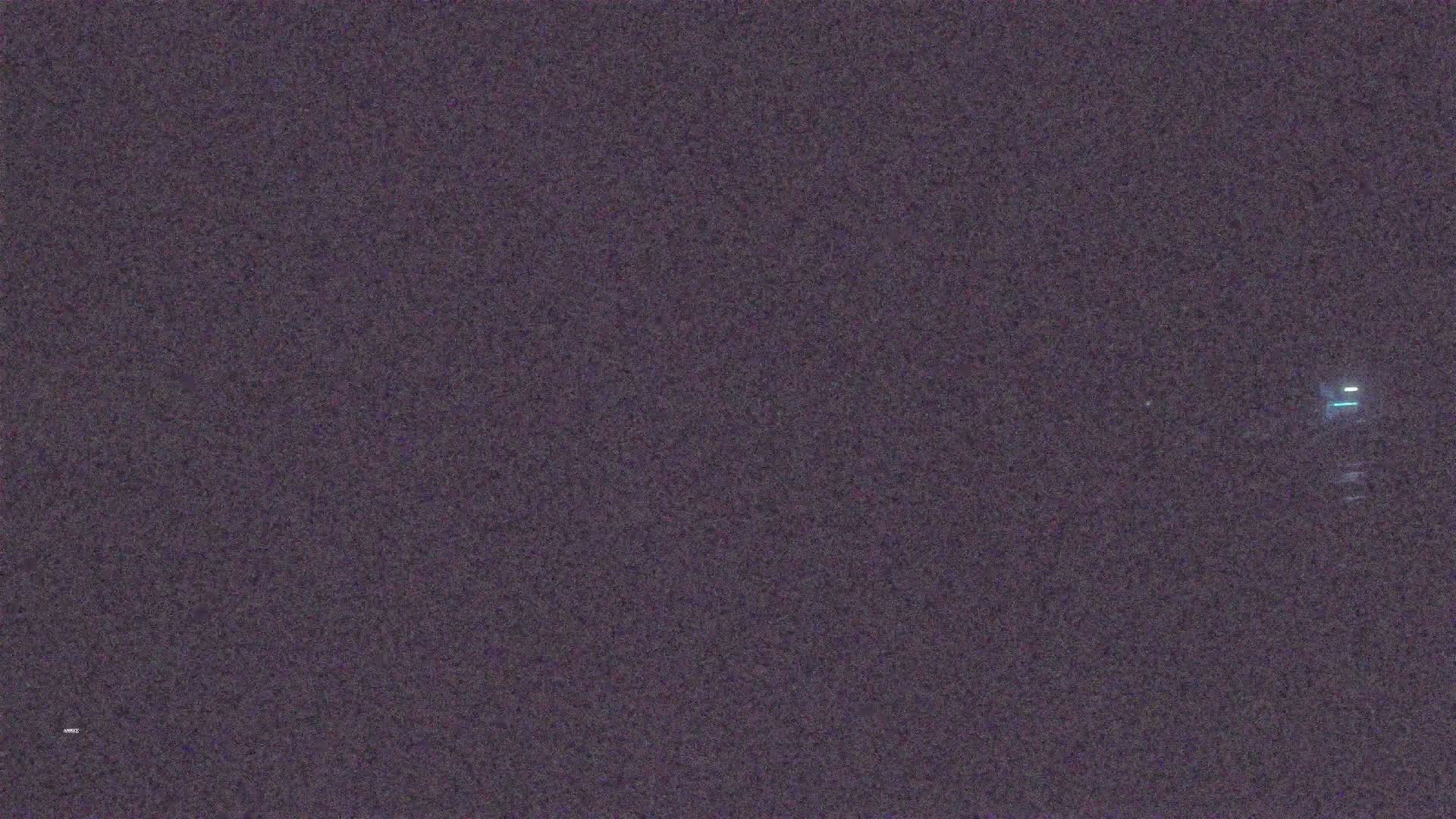 A dark, grainy image shows a faint, distant light at night.