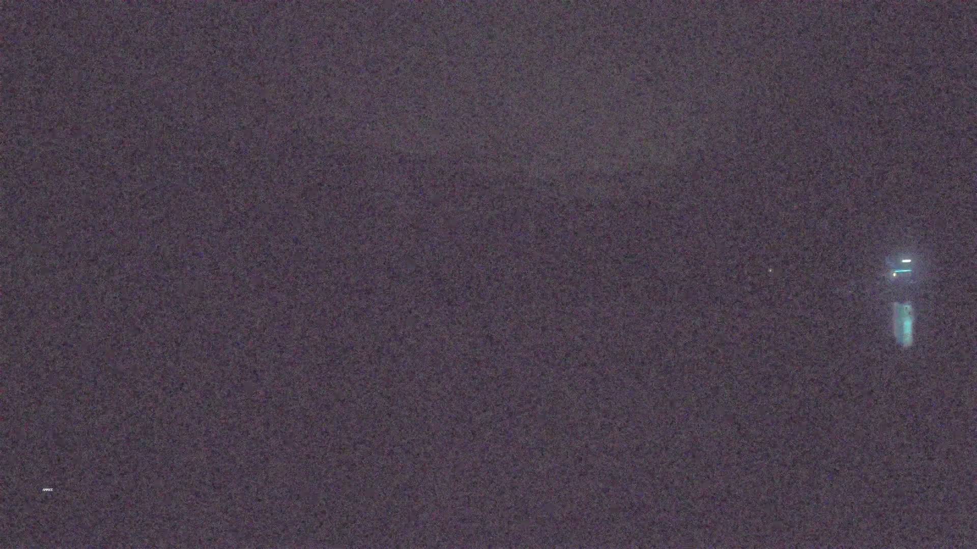 A blurry, dark image shows a faint light in the distance on a night with seemingly clear skies.