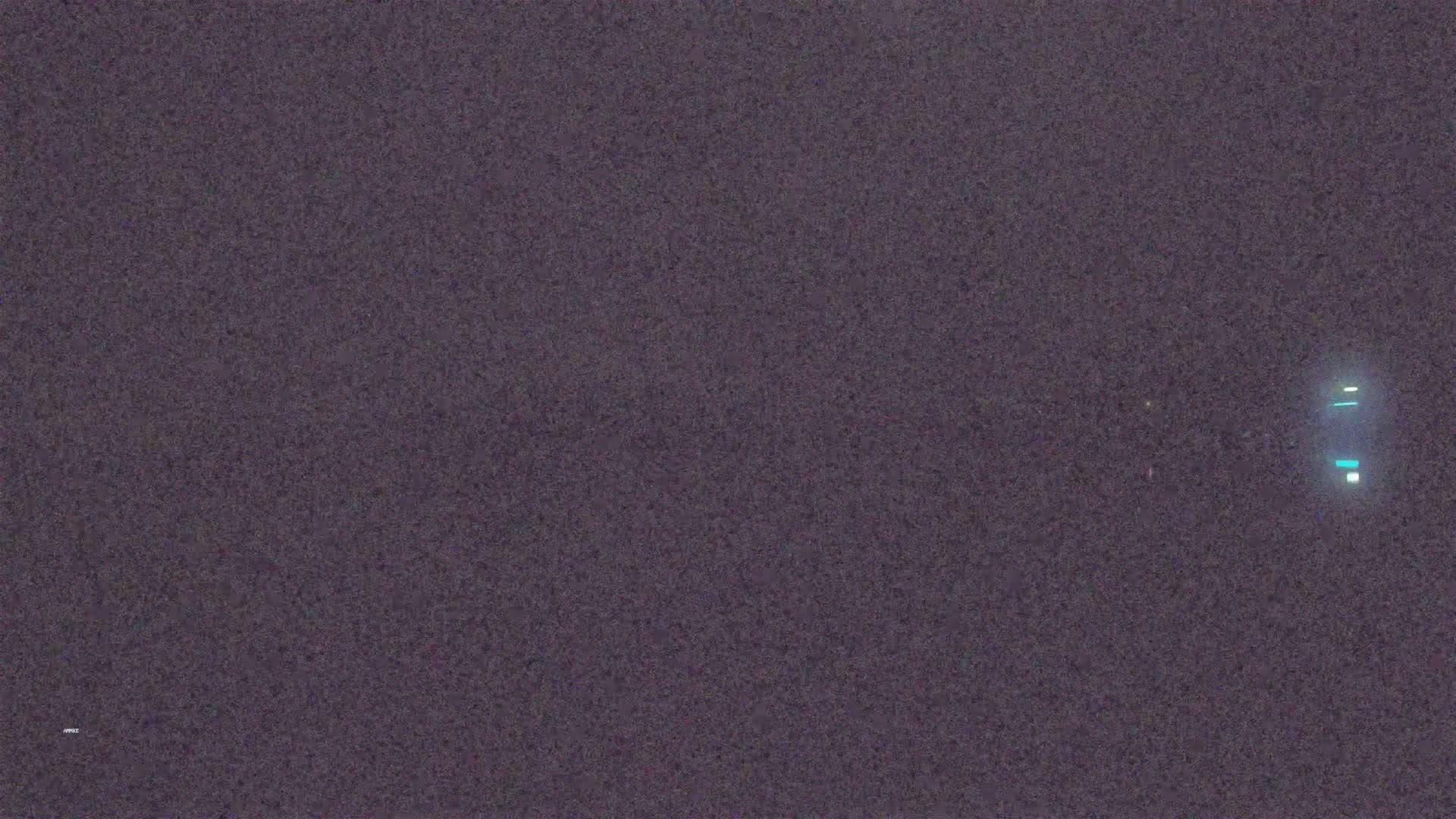 A dark, grainy image shows a faint, vertical, light-blue structure in the lower right corner.