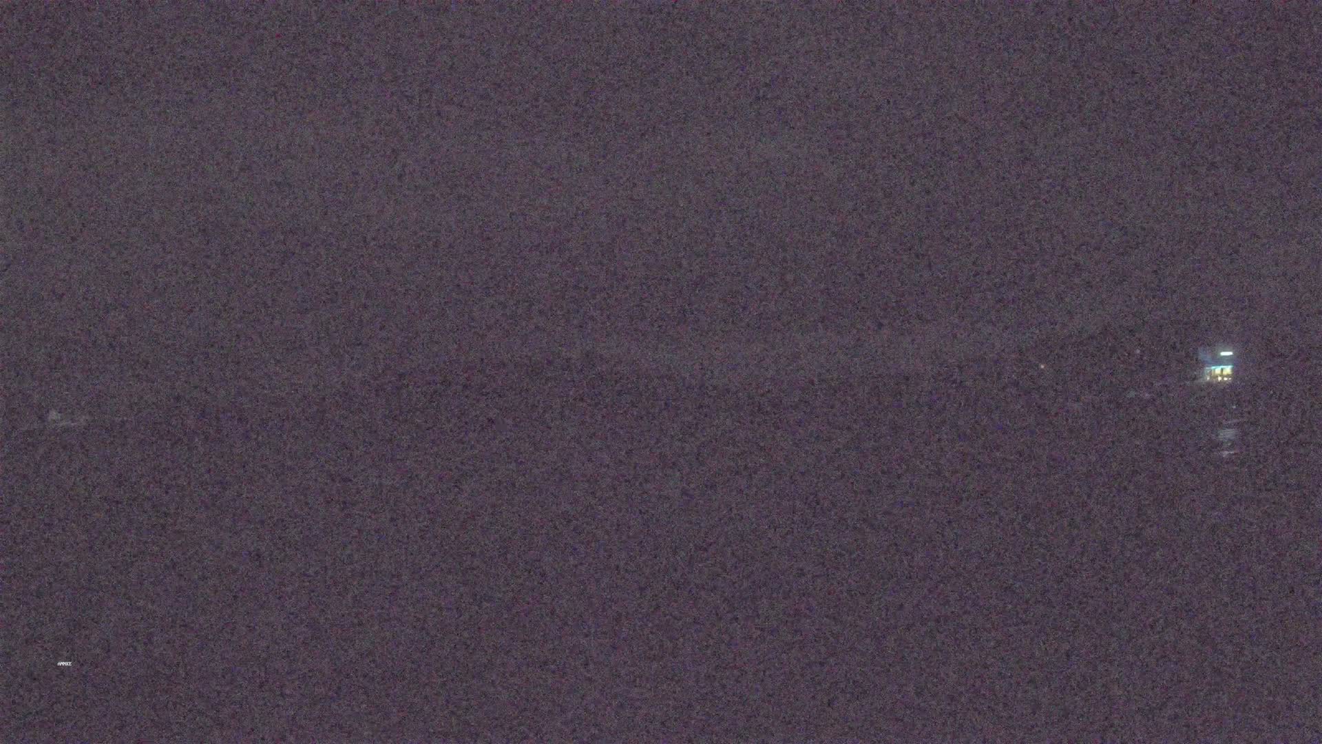 A dimly lit, dark landscape is visible at night.
