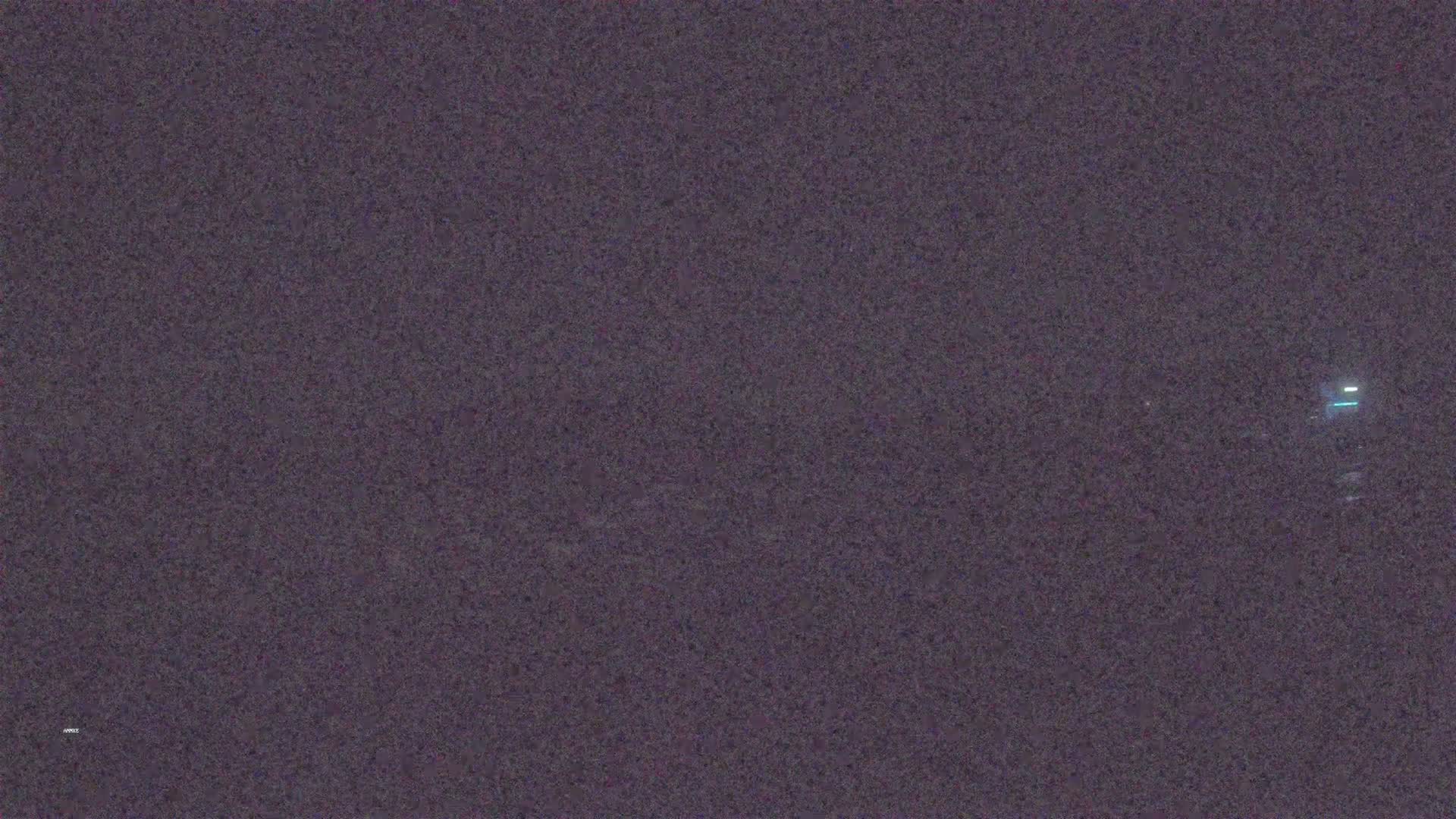 A dark, grainy image shows a faint light in the distance at night.
