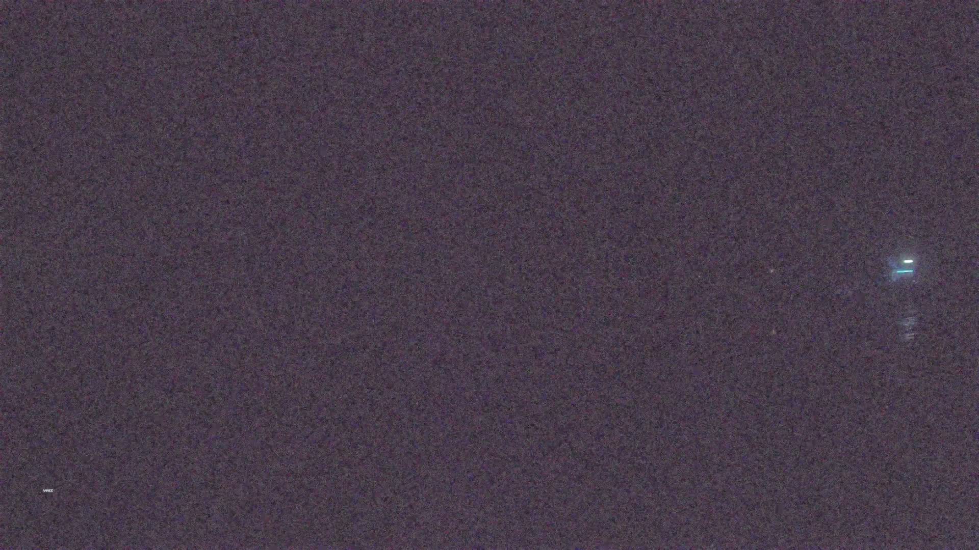 A dark, grainy image shows a faintly visible light source in the distance at night.
