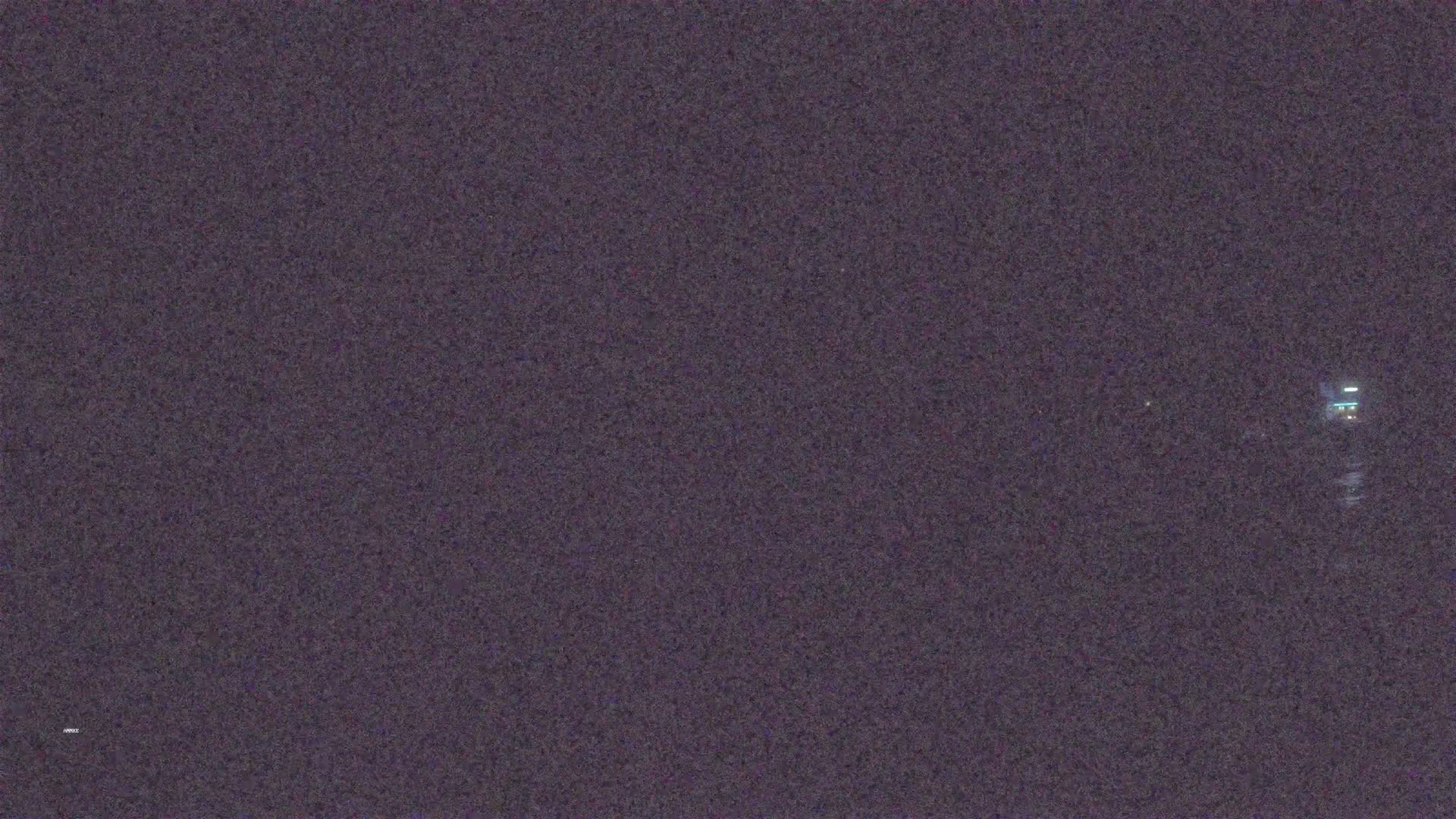 A dark, possibly nighttime scene shows a faint, distant light source.
