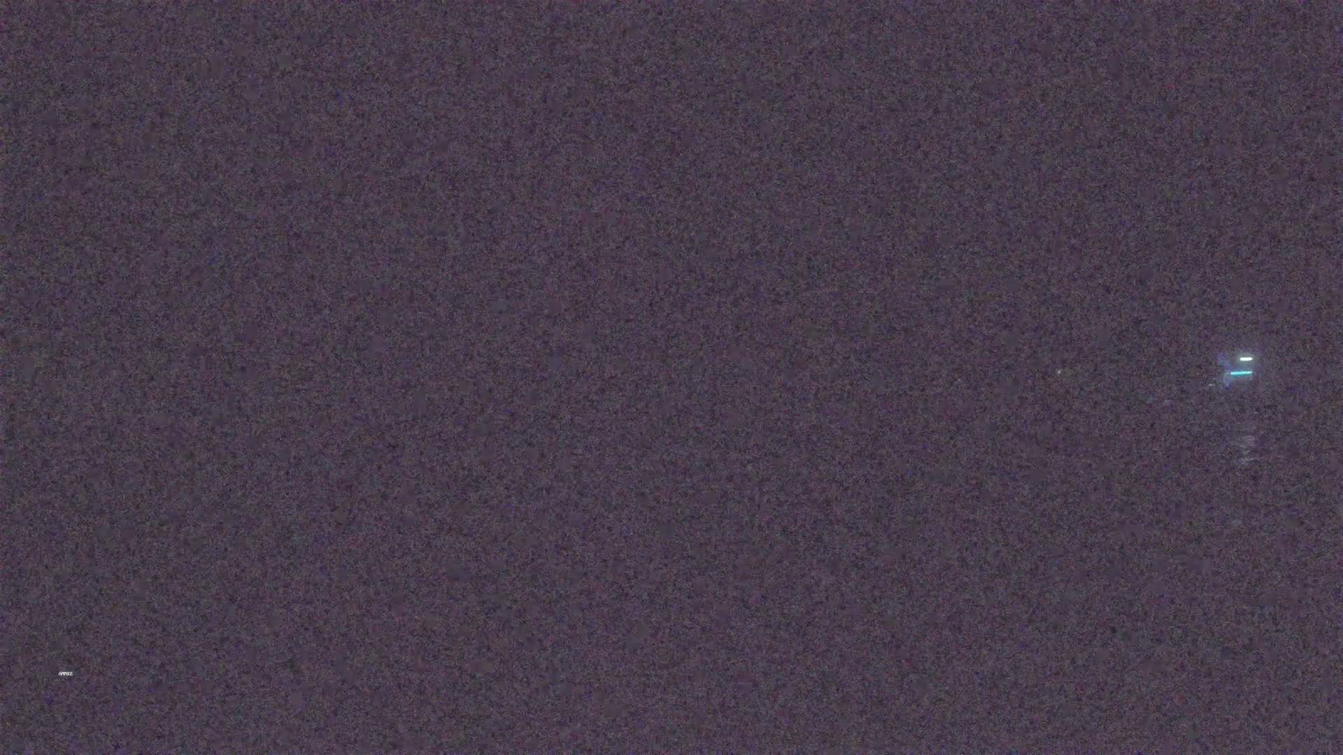 A dark, grainy image shows a faint light in the distance at night.