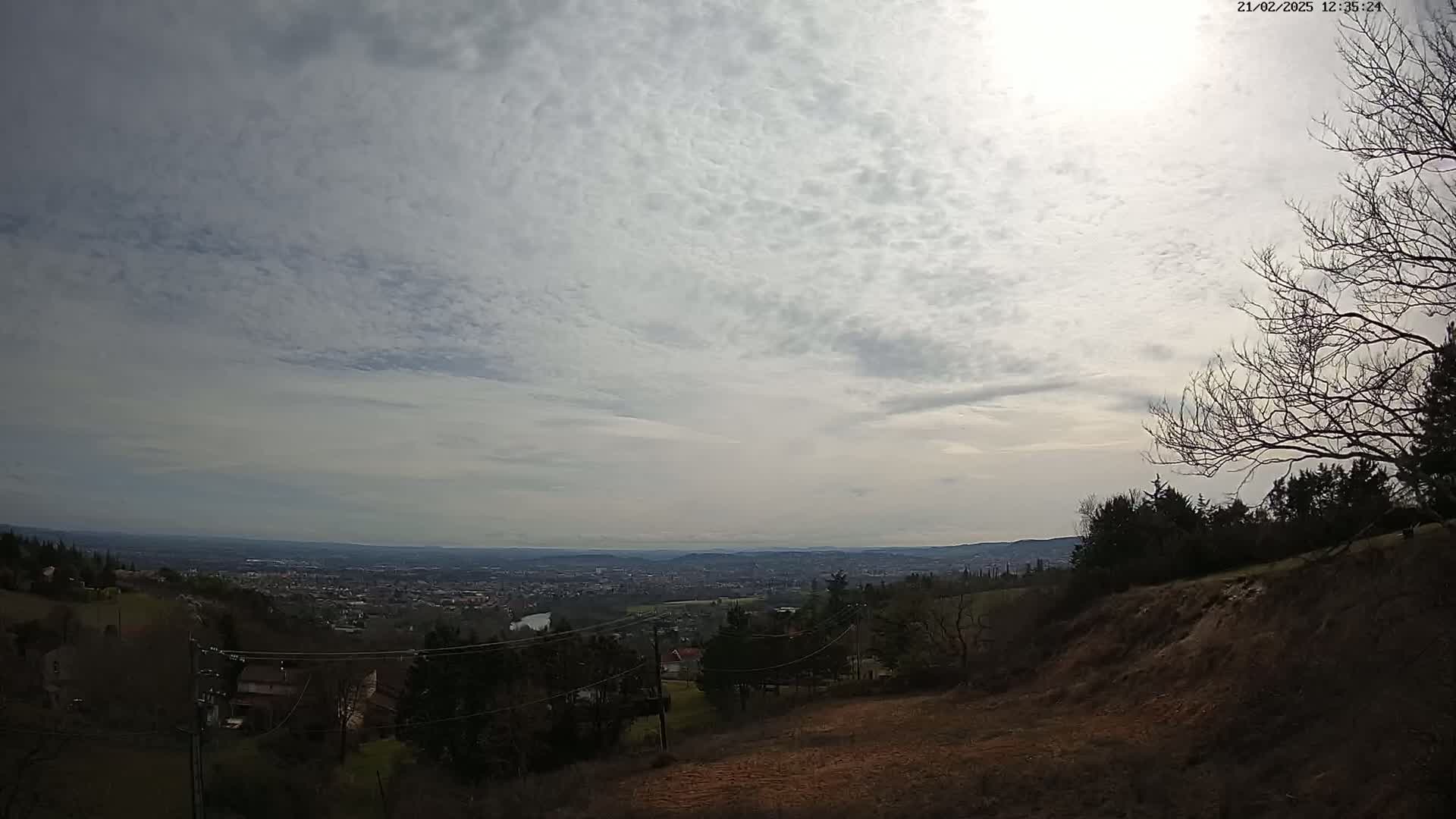 A view from a hilltop shows a sprawling city under a mostly cloudy sky.