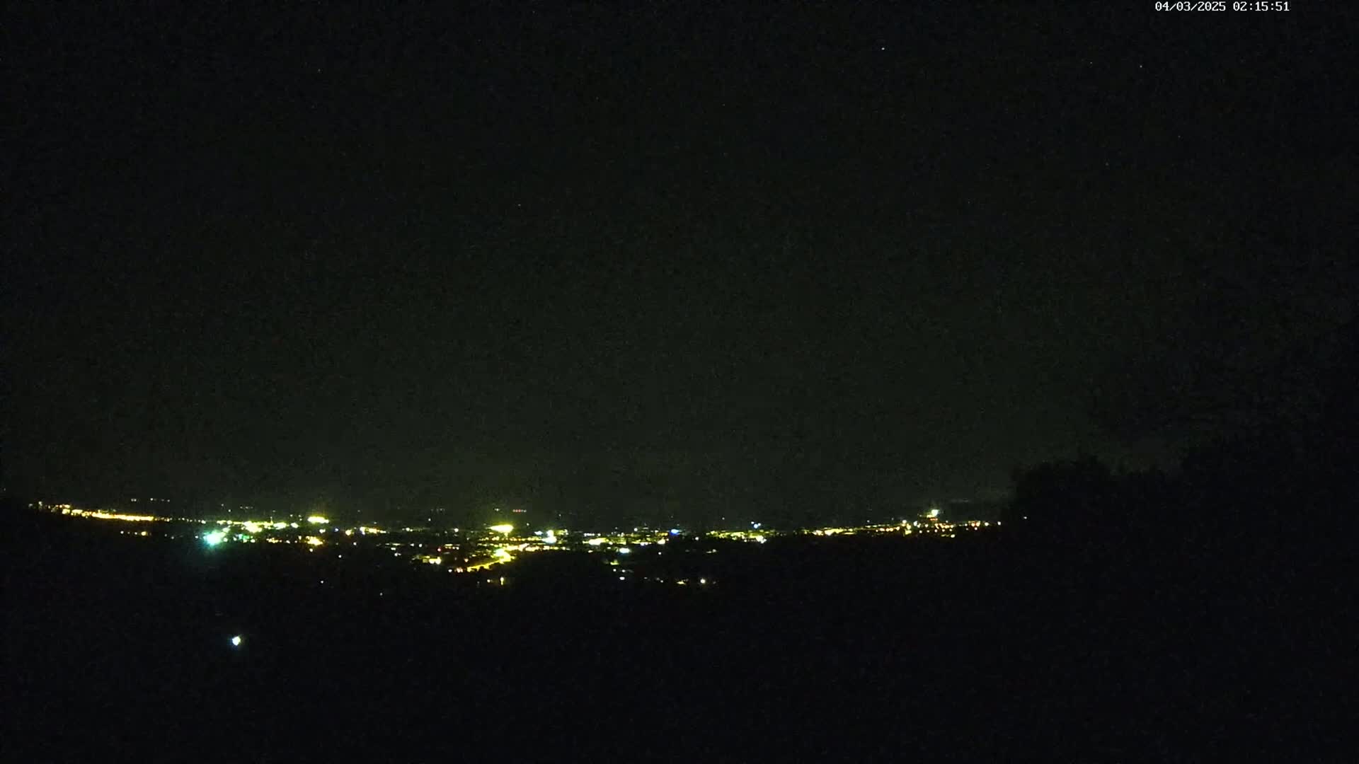 A distant city's lights illuminate a dark, clear night sky.