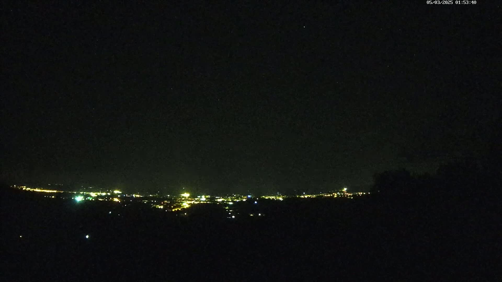 A distant city's lights are visible on a clear night from a high vantage point.