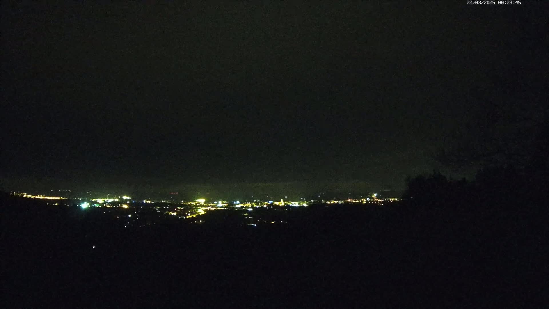A nighttime view of a distant city's lights illuminated against a dark sky.