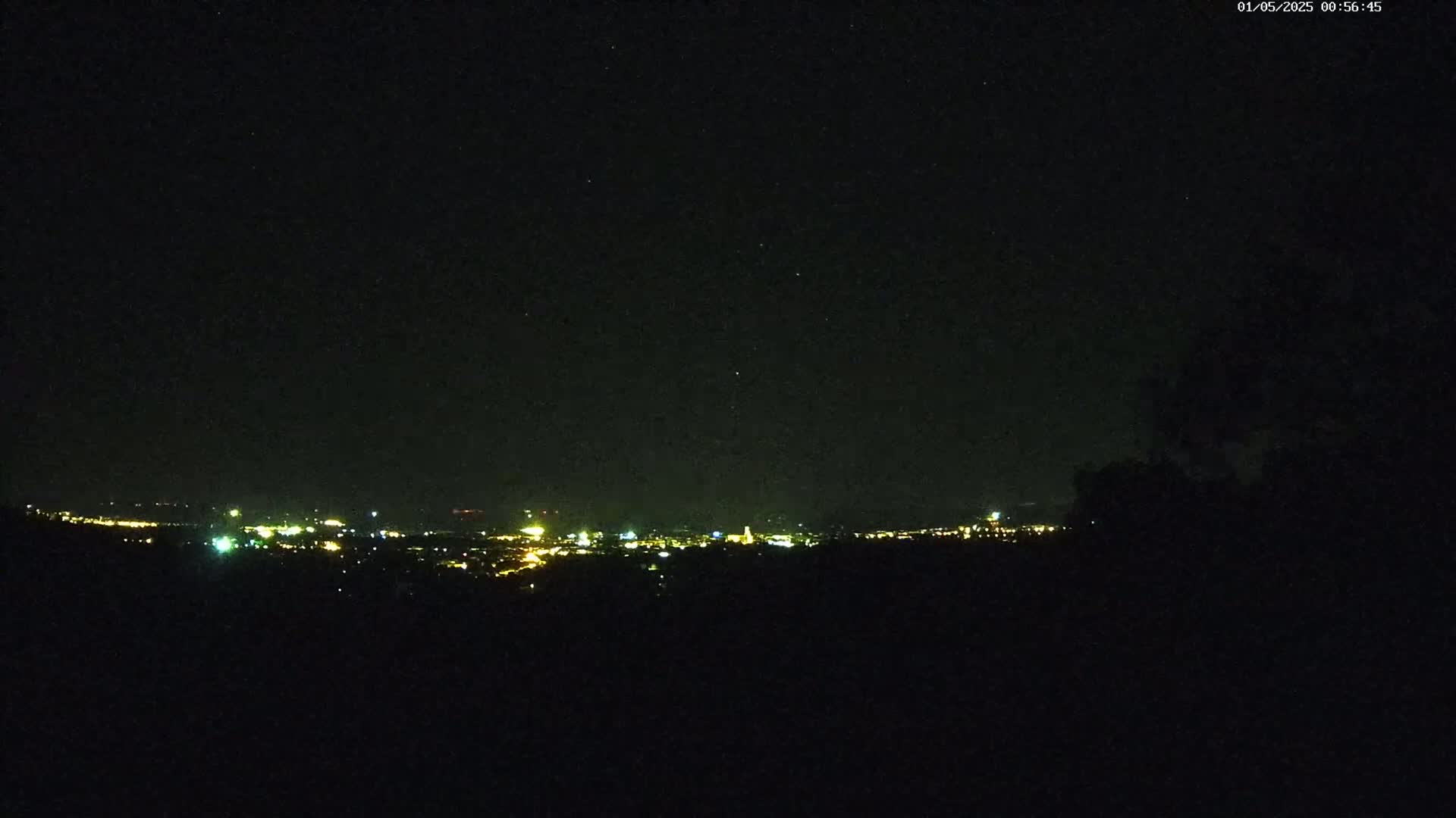 A distant city glows with faint yellow lights under a clear, dark night sky.