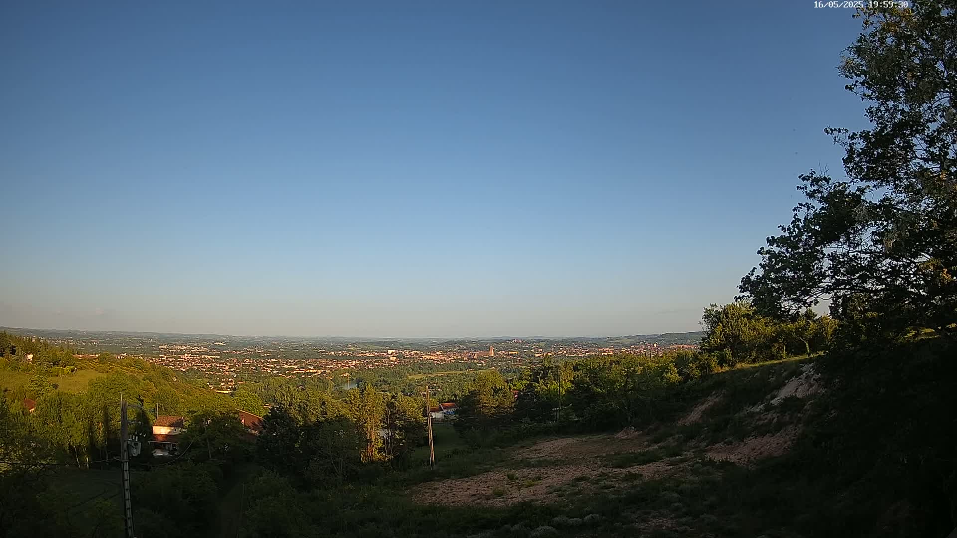 A hilltop view overlooking a sprawling city under a clear blue sky.