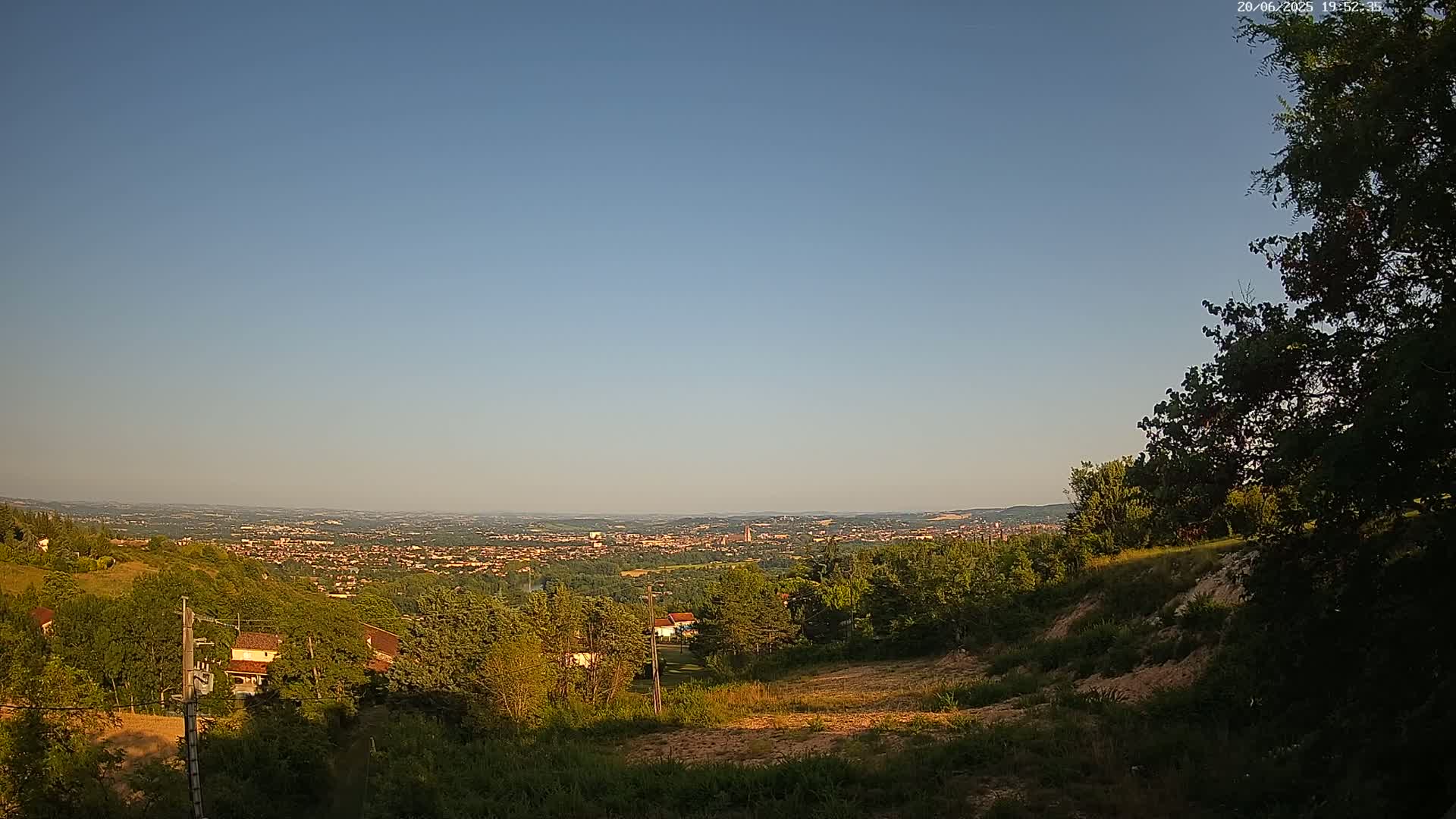 A hillside overlooking a sprawling town under a clear, blue sky.