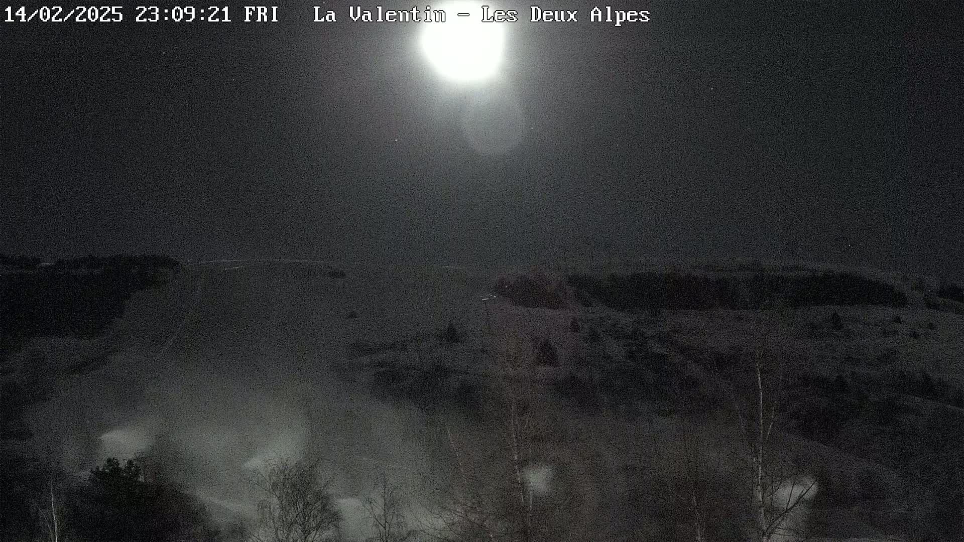 A bright moon illuminates a snow-covered landscape at night.