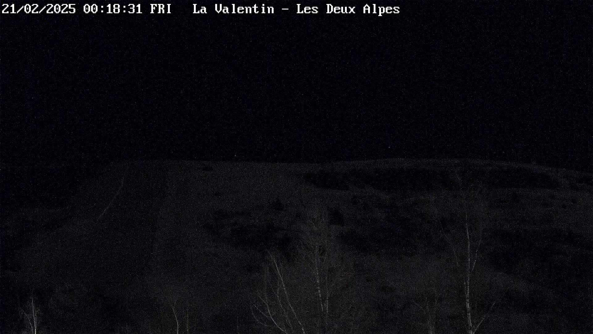 A nighttime, low-light view of a snow-covered hill or mountain landscape.