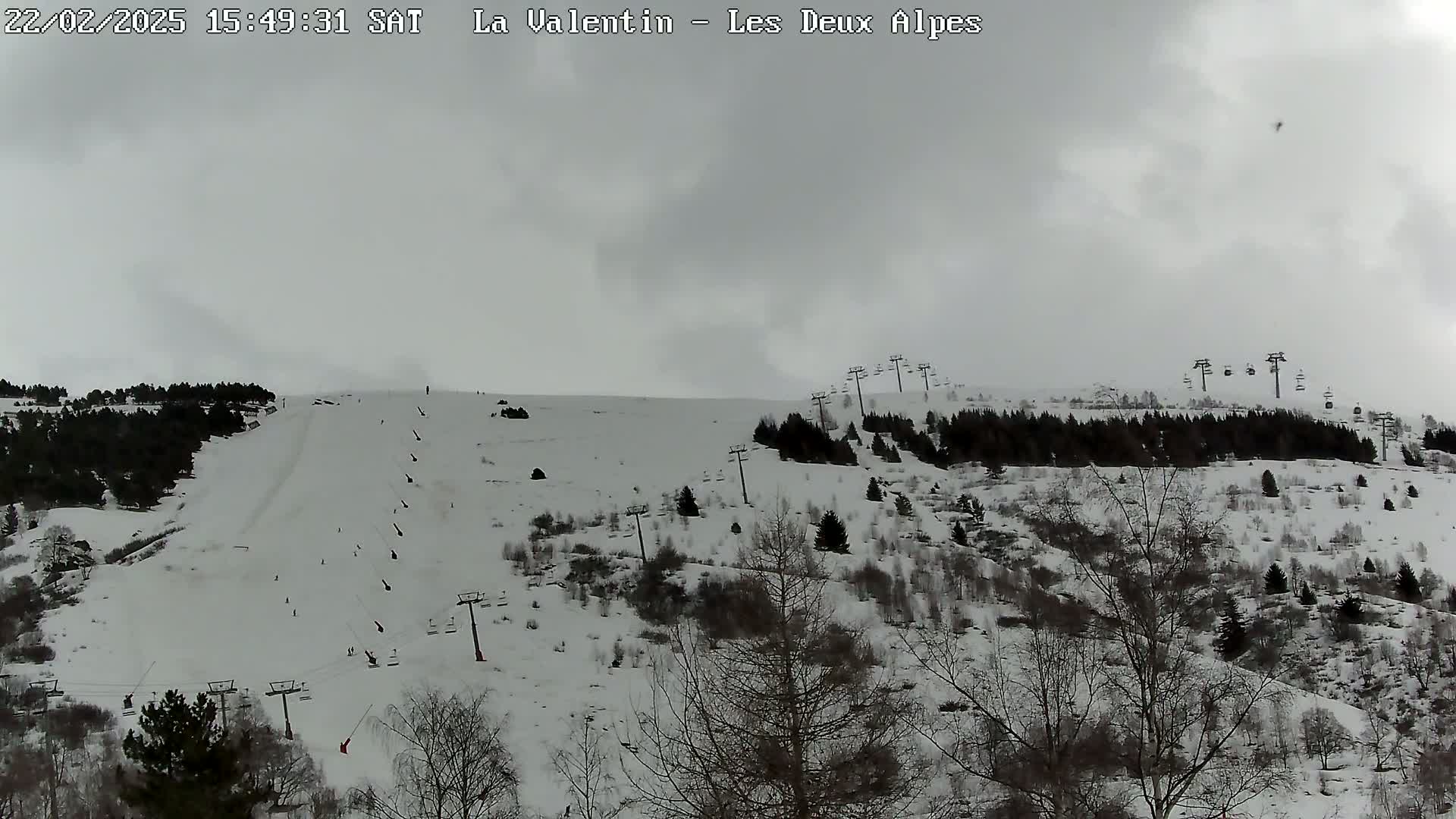 A snow-covered ski slope with several chairlifts and sparsely wooded areas under an overcast sky.
