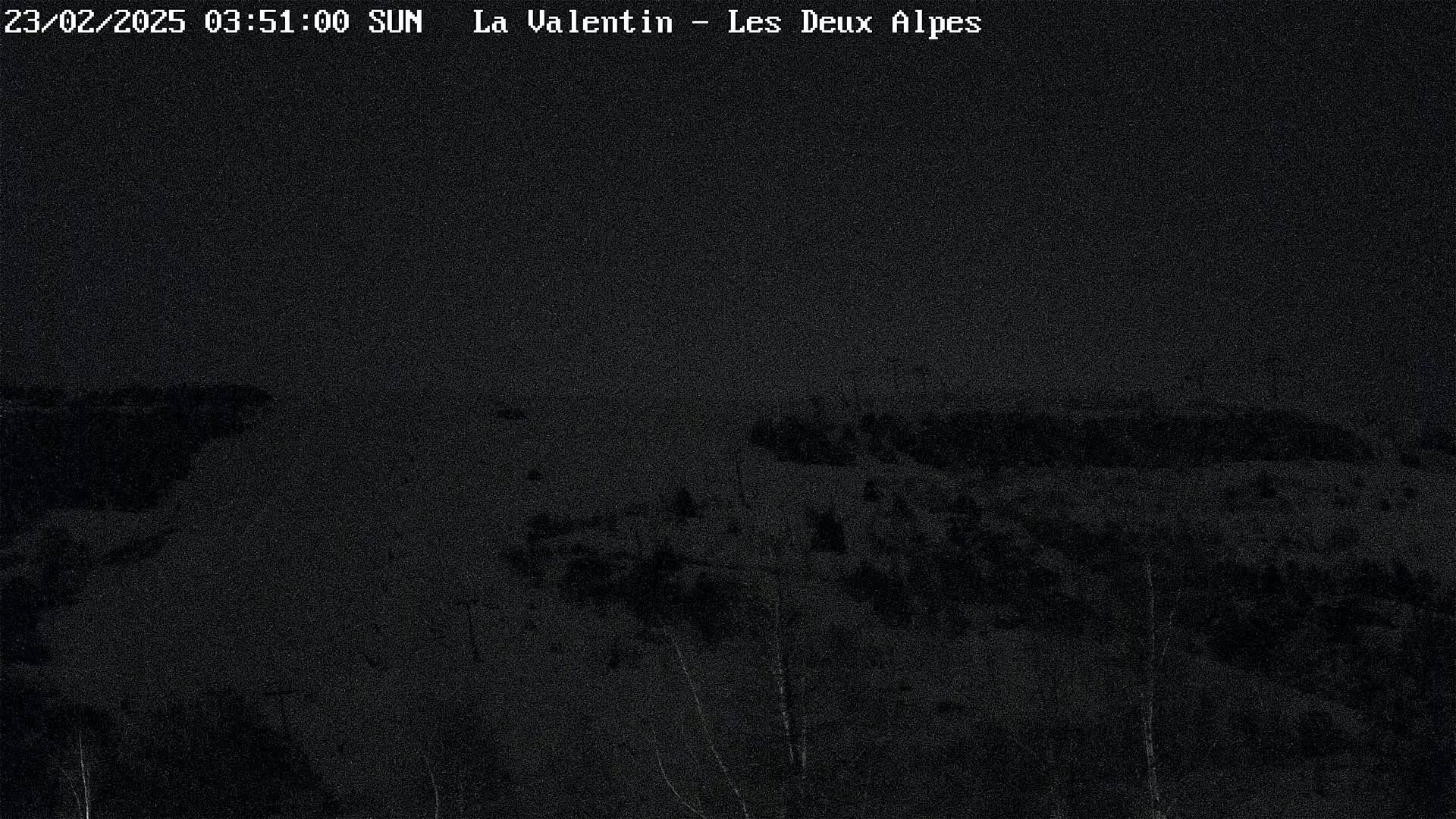 A dark, nighttime view of a snow-covered landscape.