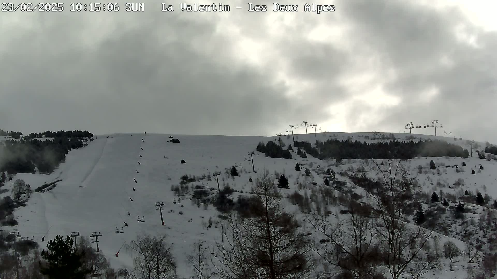 A snow-covered ski slope with several chairlifts is visible under a cloudy sky.