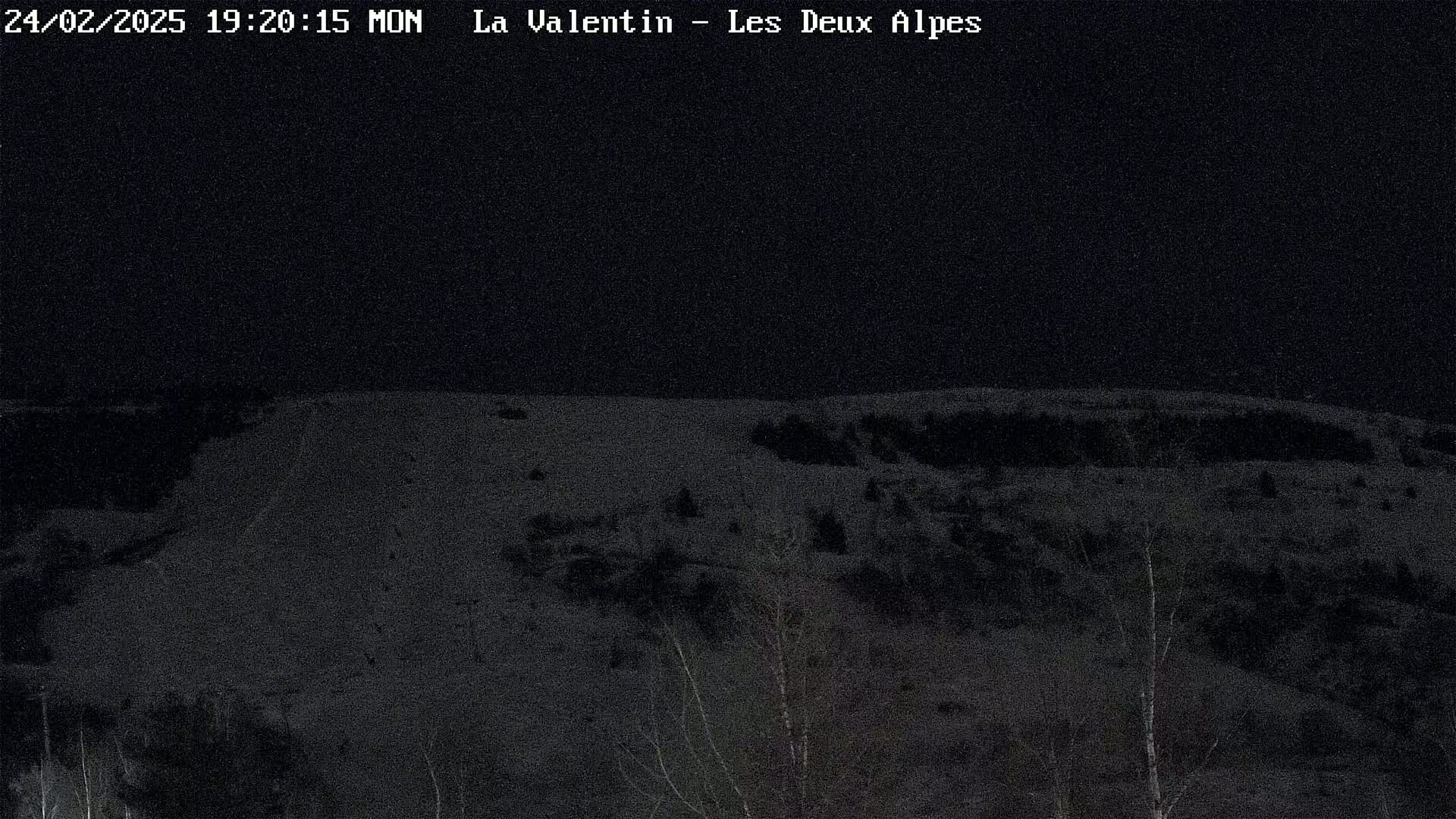 A nighttime view of a snow-covered hillside under a dark sky.