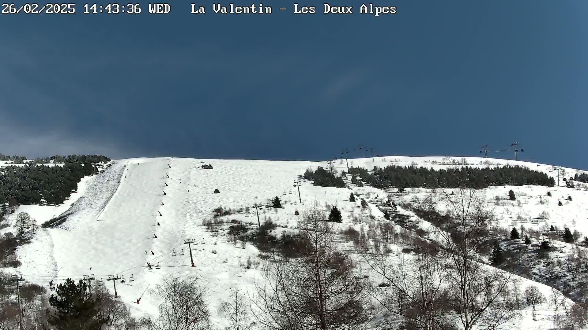 A snow-covered ski slope with several ski lifts is visible under a clear blue sky.