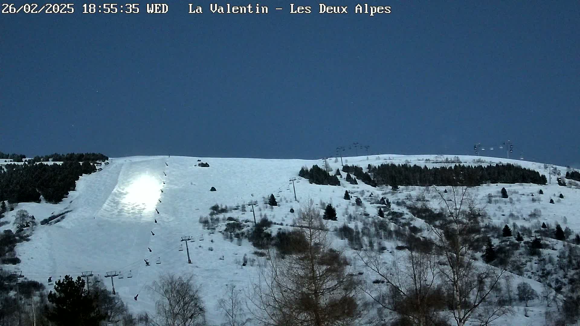 A snow-covered ski slope with ski lifts under a twilight sky.