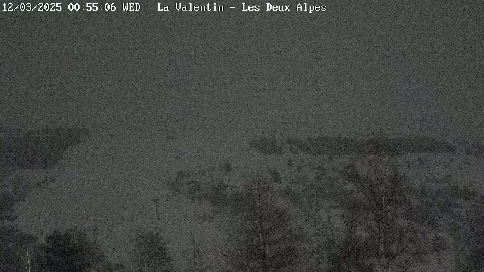 A snow-covered landscape with sparsely scattered trees is visible under a dark, overcast sky.