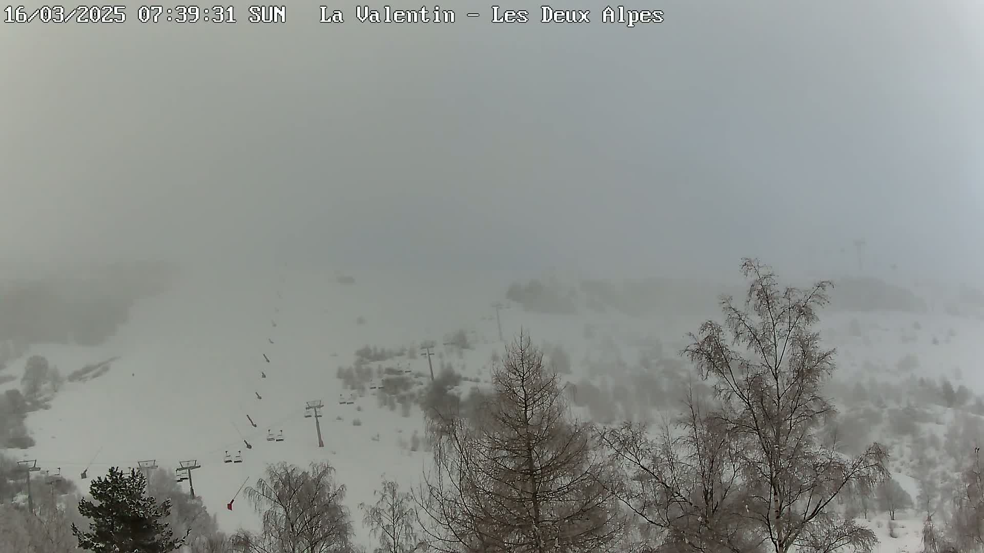 A foggy, snow-covered landscape with ski lifts and bare trees is visible from a high vantage point.