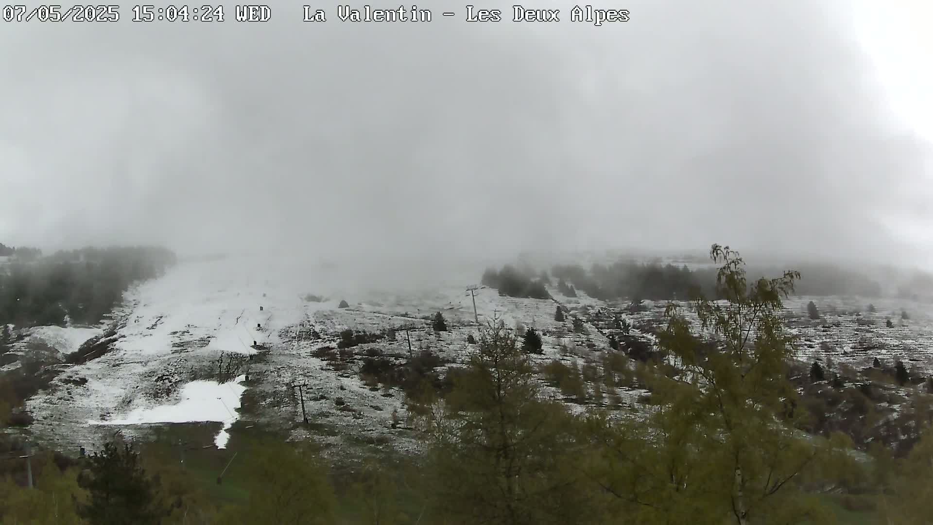 A foggy, snowy mountainside with sparse trees and ski lifts is visible.